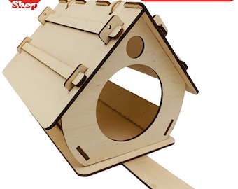 May include: A wooden bird feeder shaped like a house with a small opening for birds to access the food. The feeder has a perch for birds to land on and a small roof with a rope for hanging. The feeder is made of light brown wood and is ready to be assembled.