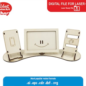 May include: Laser cut wooden phone stand with three slots for phones or pictures. The stand has a curved base and a smiling face design.