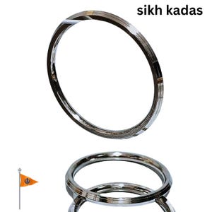May include: Shiny silver Sikh kada bracelets. The image shows two circular bracelets with a polished, reflective surface. The text "sikh kadas" is visible in the upper right corner. A small flag with an orange and yellow design is also present.