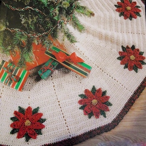 May include: Cream-colored crocheted Christmas tree skirt with red poinsettia flower appliqués and a dark red border. Presents wrapped in striped paper with red bows are visible near the tree.