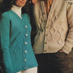 May include: Two knitted cardigans. One is teal with large buttons and a cable knit design. The other is beige with a similar cable knit pattern and wooden buttons. Both are long-sleeved.