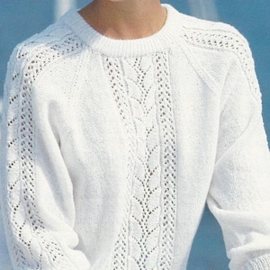 May include: A white knit sweater with a crew neck and long sleeves. The sweater features a detailed openwork design down the center and on the sleeves. The cuffs and hem are ribbed.