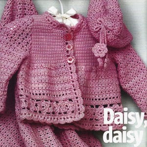 May include: A pink crochet baby set, including a jacket with buttons, a bonnet, and a blanket. The jacket has a scalloped edge and the bonnet has a flower accent. The text "Daisy, daisy" is visible in the image.