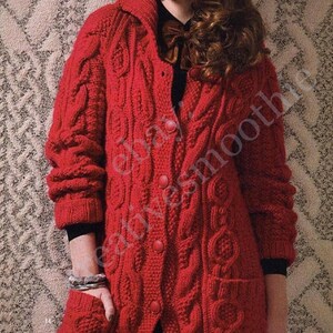 May include: A long, red cable-knit cardigan with a button-up front, pockets, and a collar. The sleeves are long, and the cardigan appears to be made of a thick, warm yarn. The overall style is classic and cozy.
