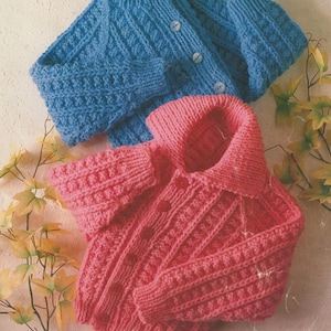 May include: Two knitted children's jackets, one blue and one pink, are displayed. The blue jacket is buttoned and has a round collar. The pink jacket is also buttoned and has a collar. The jackets are made of a chunky knit yarn.