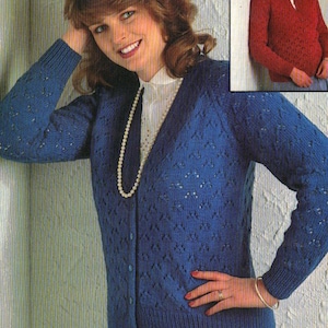 May include: A blue knitted cardigan with a V-neck and button closure. The cardigan features a textured pattern and is worn over a white blouse and a pearl necklace. A smaller image shows a red knitted sweater.