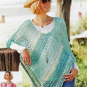 May include: A woman wearing a straw hat and sunglasses, with a turquoise and white crochet poncho over a white long-sleeve shirt and blue jeans. The poncho has a gradient color pattern. A necklace with a pendant is visible.