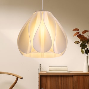 May include: White pendant light fixture with a unique, flower-shaped shade. The shade is made of multiple overlapping petals, creating a soft, diffused light.