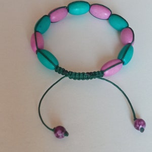 May include: A green and pink beaded bracelet with a knotted closure and purple accent beads.
