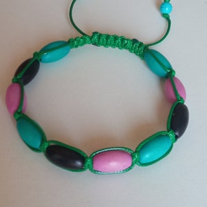 May include: A green string bracelet with pink, turquoise and black oval beads.