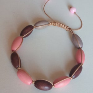 May include: A brown, pink, and gray beaded bracelet with a knotted cord closure.