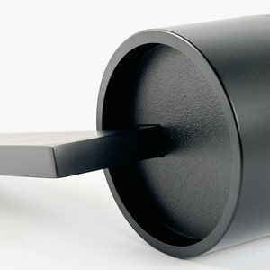 May include: A black wooden door handle with a cylindrical design. The handle has a flat, rectangular base and a round, protruding knob.