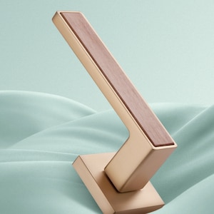 May include: A gold door handle with a wooden insert. The handle is designed with a square base and a lever.