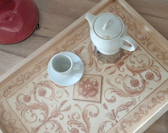 May include: A white wooden tray with a decorative floral pattern in shades of brown and beige. The tray features a white teapot and a white cup and saucer.