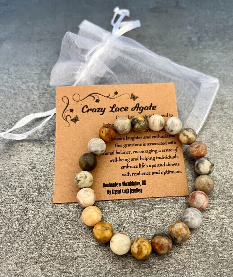 May include: A brown and white Crazy Lace Agate bracelet with a card that reads "Crazy Lace Agate" and describes the gemstone's properties. The card also states "Handmade in Warwickshire, UK by Crystal Craft Jewellery".