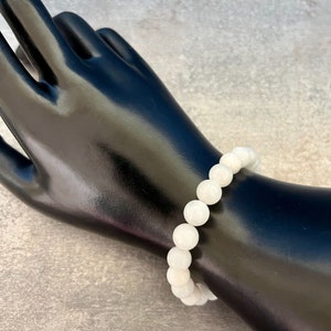 May include: White gemstone bracelet with round beads.