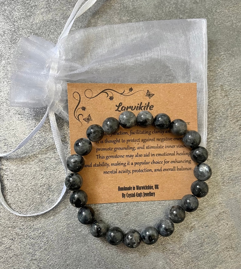 May include: A black Larvikite gemstone bracelet with 18 beads. The bracelet is handmade in Warwickshire, UK by Crystal Craft Jewellery. The card includes information about the healing properties of Larvikite.