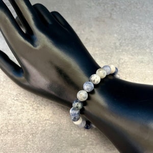 May include: A blue and white gemstone bracelet with round beads. The bracelet is made of natural stones and is approximately 7 inches in length.