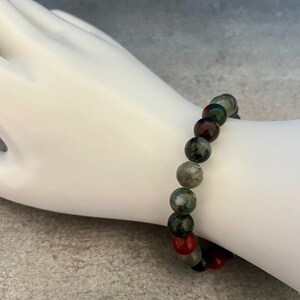 K&ouml;nnte beinhalten: Ein Armband aus gr&uuml;nen, roten und schwarzen Edelsteinperlen.