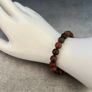 May include: A bracelet made of brown, red, and green gemstone beads.