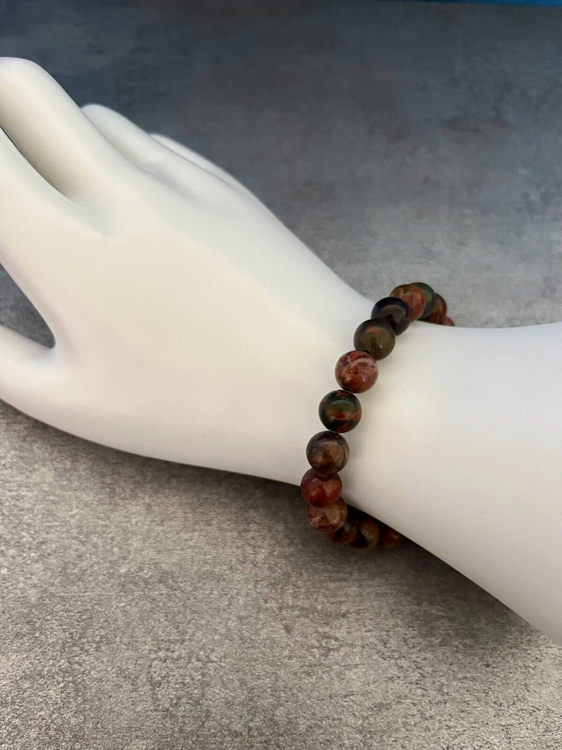 May include: A bracelet made of brown, red, and green gemstone beads.