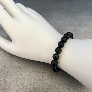 Op de afbeelding: Een zwarte armband met ronde kralen.