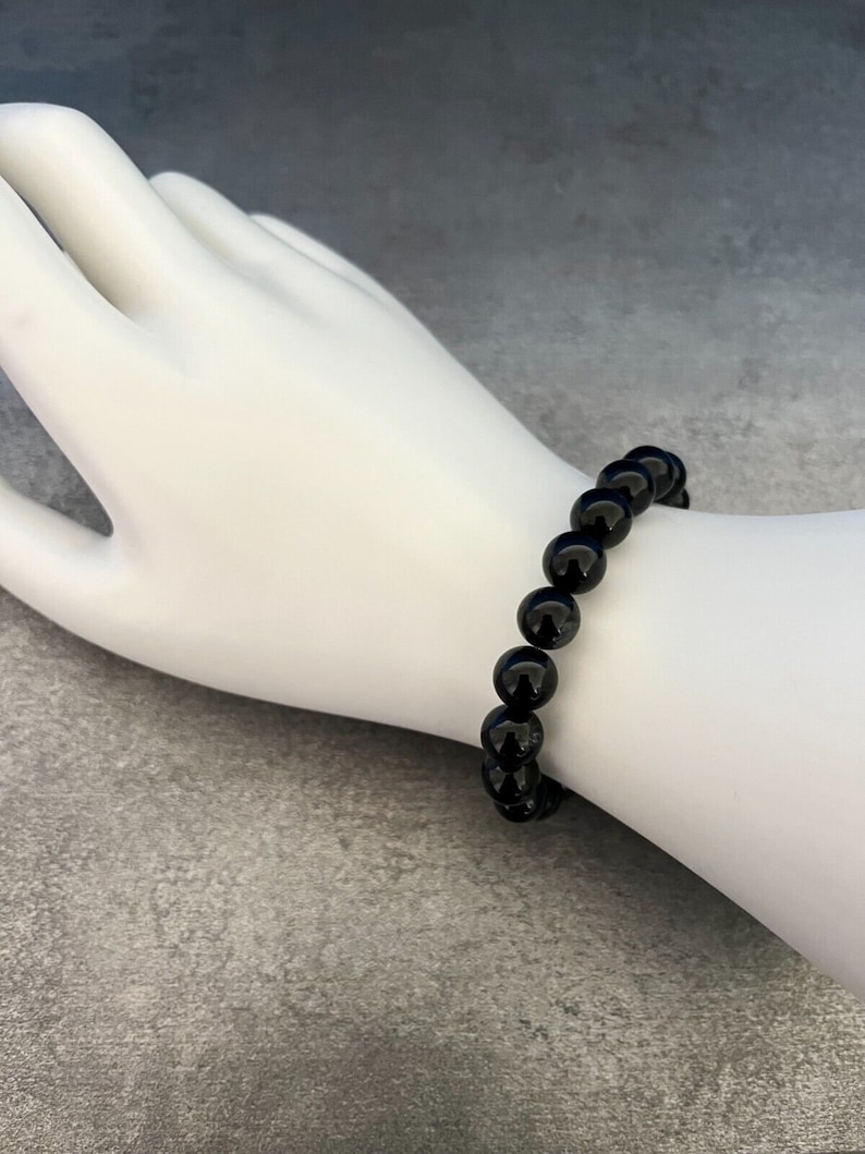 Op de afbeelding: Een zwarte armband met ronde kralen.
