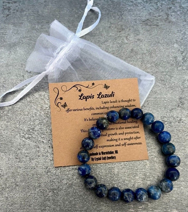May include: A blue lapis lazuli gemstone bracelet with a brown card that reads "Lapis Lazuli" and describes the benefits of the stone. The bracelet is made in Warwickshire, UK by Crystal Gift Jewellery.
