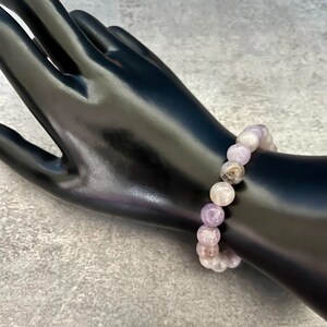 May include: A purple and white gemstone bracelet with round beads.