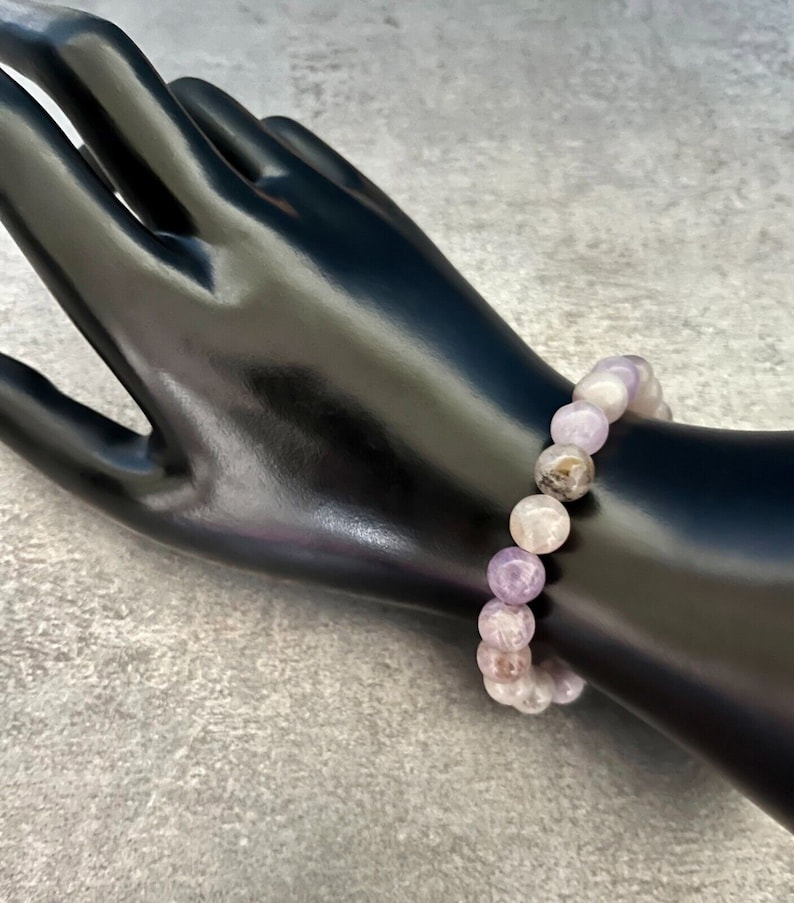 May include: A purple and white gemstone bracelet with round beads.