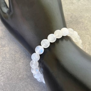 May include: A white moonstone beaded bracelet with a stretchy elastic band.