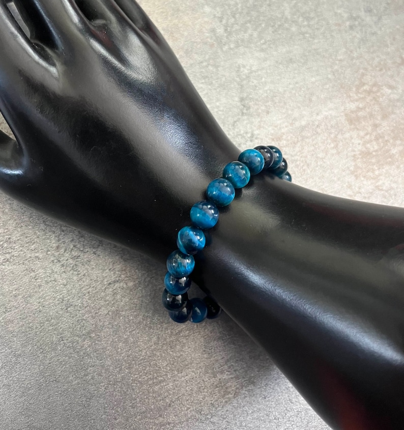 May include: A blue tiger's eye beaded bracelet. The bracelet is made of round beads and is strung on elastic.