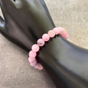 May include: A pink and black beaded bracelet with a stretchy elastic band.