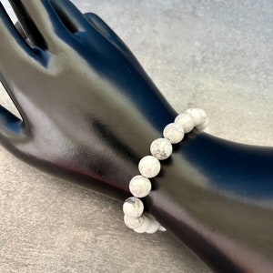 May include: White howlite beaded bracelet with a stretchy elastic band. The beads are round and have a marbled pattern.