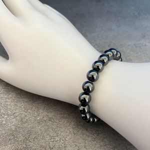 May include: A black beaded bracelet with round, shiny beads.