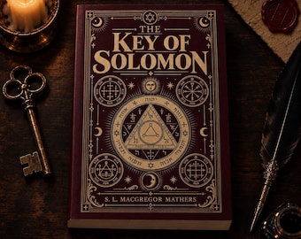 May include: A maroon hardcover book titled The Key of Solomon by S. L. MacGregor Mathers, featuring gold geometric symbols, Hebrew text, and celestial motifs on the cover, accompanied by a metal key, a lit candle, and a quill pen.