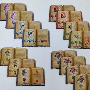 Puede incluir: Un conjunto de 16 cartas de juego coloridas con ilustraciones de varias criaturas y plantas. Cada carta tiene un número y una regla única para jugar al juego. Las cartas están diseñadas para parecer libros abiertos.