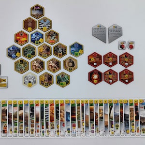 May include: A game board with hexagonal tiles, cards, and dice. The tiles are yellow with gold trim and feature various symbols. The cards are white with blue and orange accents. The dice are red and white.