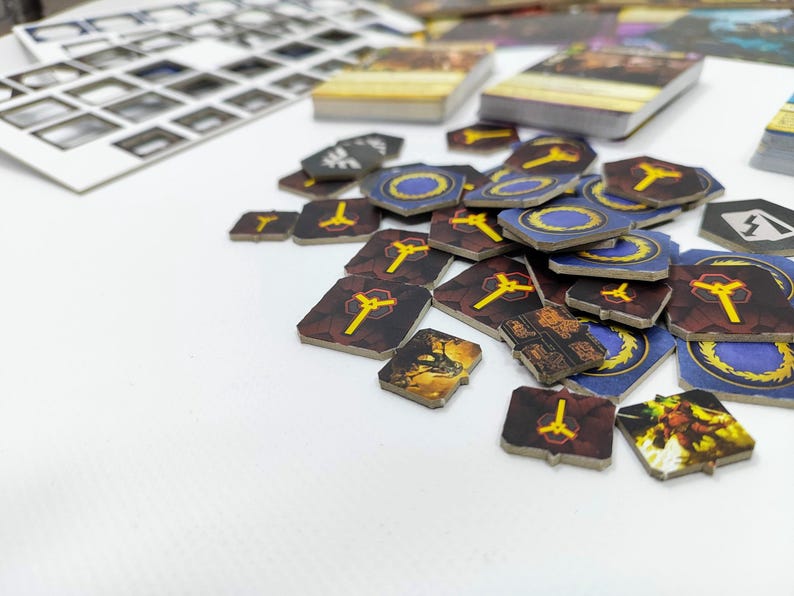 May include: A collection of board game components, including wooden tokens and card stacks. The tokens feature various designs with yellow and blue accents. The game pieces are scattered on a white surface, suggesting gameplay.