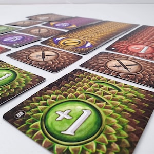 May include: A set of game cards with different numbers and symbols. The cards have a brown background with a green, leafy pattern. The symbols include a sword and a plus sign.