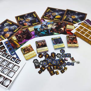 May include: A collection of board game components, including game boards depicting planets, character cards, and various tokens. The color palette includes blues, browns, yellows, and purples, suggesting a space or fantasy theme. The components are arranged on a white surface.