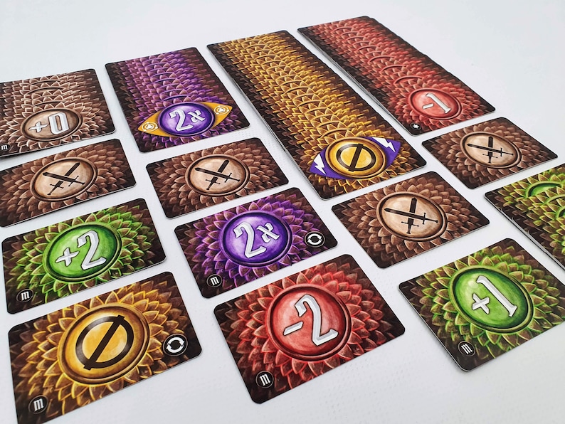 May include: A set of game cards with different symbols and numbers. The cards have a brown, green, purple, or orange background with a circular design. The symbols include swords, a zero, and a 2x multiplier. The numbers include +0, +1, +2, -1, and -2.