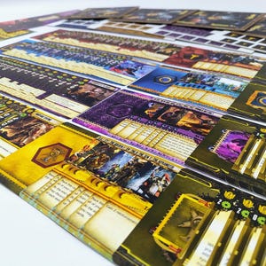May include: A collection of colorful game cards and components, featuring illustrations and text. The cards have a variety of designs, including images of characters and symbols, with a mix of yellow, purple, and blue hues. The cards are arranged on a white surface.