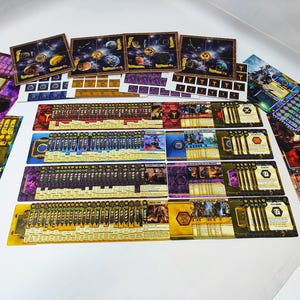 May include: A collection of board game components, including cards, game boards, and tokens. The cards feature various illustrations and text, with a color palette of gold, purple, and blue. The game boards depict celestial scenes.