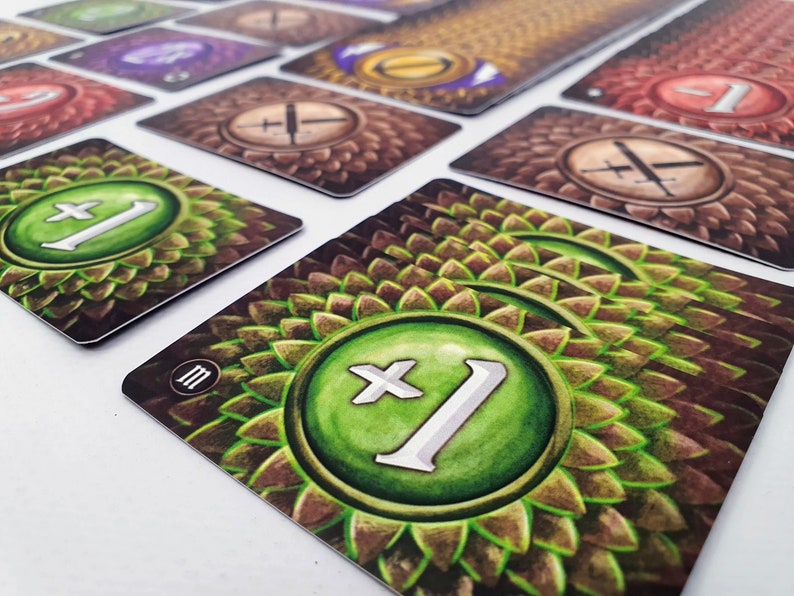 May include: A green and brown card game tile with a green circle containing a white plus sign and the number 1. The tile has a brown background with a pattern of overlapping green scales.