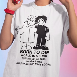 以下が含まれることがあります： 白のTシャツ。2人の漫画のキャラクターが抱き合っている白黒のグラフィックが特徴です。Tシャツには「BORN TO DIE」、「WORLD IS A FUCK」、「鬼神 Kill Em All 2018」、「I am devil man」、および「410,757,864,530 TIME LOOPS」というテキストが含まれています。