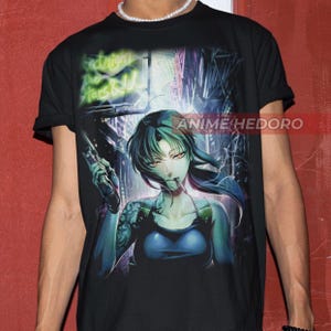 Puede incluir: Camiseta negra con un estampado gráfico de un personaje de anime sosteniendo un arma. El personaje tiene el pelo largo y negro y ojos verdes. El fondo es una escena de ciudad con luces de neón.