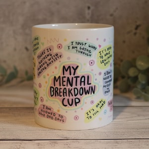 Pu&ograve; includere: Una tazza in ceramica bianca con un design colorato che presenta il testo "My Mental Breakdown Cup" e varie affermazioni positive. Le affermazioni includono "Mi fido di quello che sto attraversando", "Non c'&egrave; niente di sbagliato nell'avere ansia", "Mi &egrave; permesso avere giornate brutte", "Va bene avere giornate con poca energia", "Va bene sentirsi arrabbiati", e "Non ho bisogno di confrontarmi con gli altri".