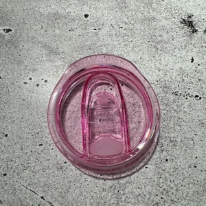 May include: A pink plastic lid for a travel mug with a silicone seal.