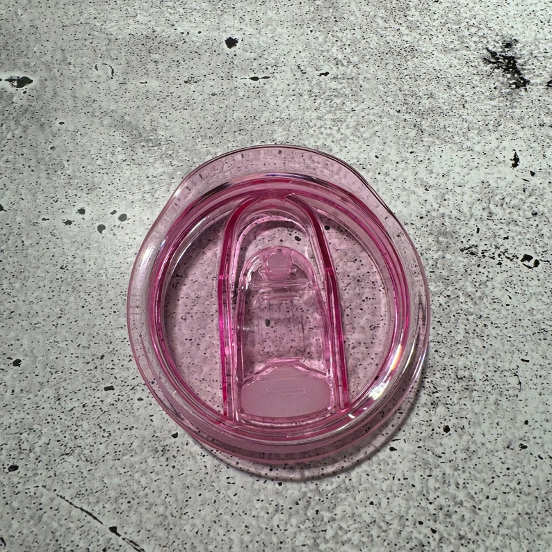 May include: A pink plastic lid for a travel mug with a silicone seal.